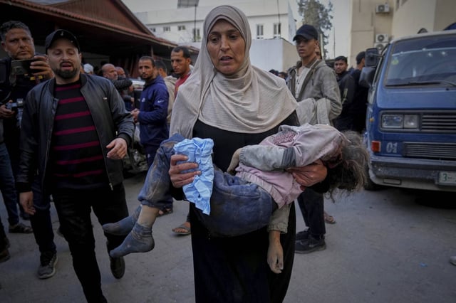 Une femme porte un enfant à l'hôpital Al-Ahli après les frappes aériennes israéliennes de la nuit dans la bande de Gaza, ce mardi 18 mars.