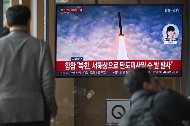 People watch a television screen showing a news broadcast with file footage of a North Korean missile test, at a train station in Seoul on March 10, 2025.