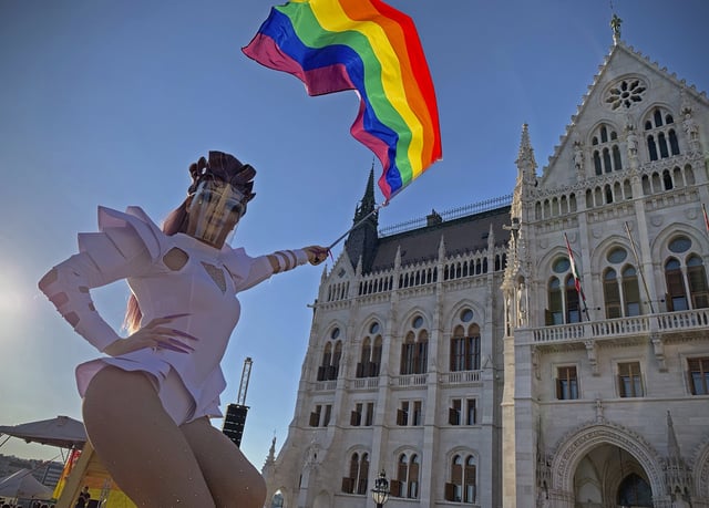 FILE - A participant waves a rainbow flag during an LGBT rights demonstration in front of the Hungarian Parliament building in Budapest, Hungary on June 14, 2021. (AP Photo/Bela Szandelszky, File)