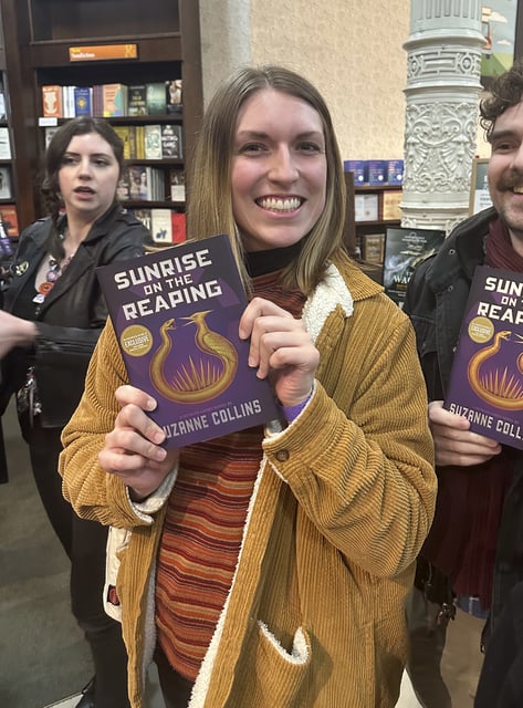 Savannah Miller holds her copy of "Sunrise on the Reaping" by Suzanne Collins at a midnight launch party at Barnes & Noble bookstore in New York on Tuesday, March 18, 2025. (AP Photo/Hillel Italie)