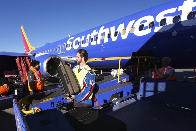 Colorado Avalanche goalie Scott Wedgewood, center, helps unload baggage from a Southwest Airlines plane at Denver International Airport on February 27, 2025. The airline will no longer permit free baggage for standard travelers beginning later this year.