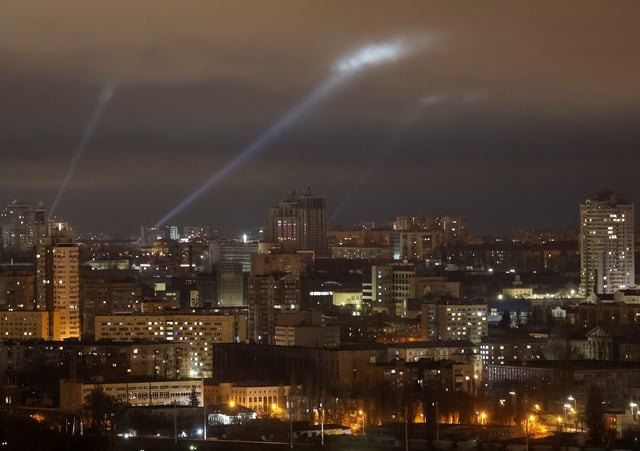 Ukrainian service personnel use searchlights to try and find drones over Kyiv during a Russian strike