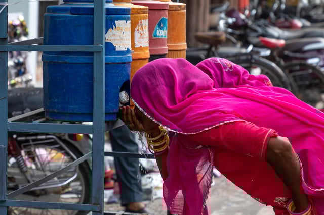 Women drinking water in the street during a heat wave in Rajasthan, India. Credit: Eric Lafforgue / Alamy Stock Photo