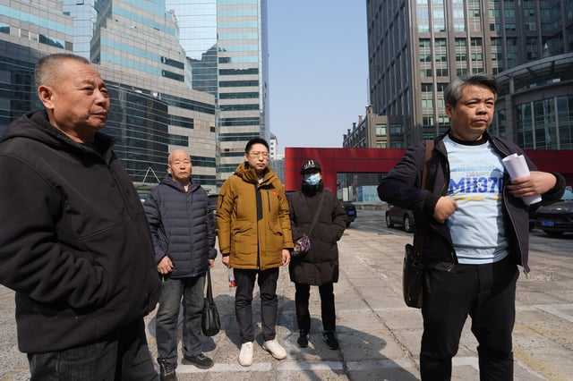 Jiang Hui, right, whose mother was on the missing MH370 Malaysia Airlines passenger jet, wears a shirt "Remembering 239 Lives, MH370" as he talks to media near other family members of victims Saturday, March 8, 2025, in Beijing, China. (AP Photo/Ng Han Guan)