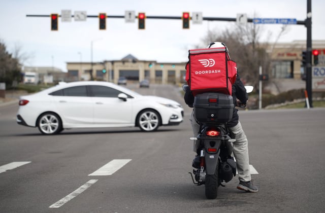 A food delivery rider for DoorDash waits for the traffic light to change to head northbound on Chester Street at County Line Road on Monday, March 30, 2020, in Lone Tree, Colorado.