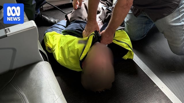 Several people holding down a teenage boy in an aeroplane
