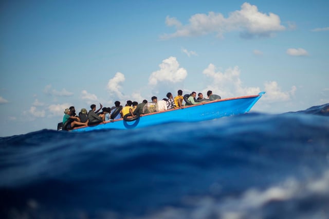 Migranten sitzen in einem Holzboot im Mittelmeer