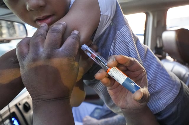 Renee Barbian gives an insulin shot to her immunocompromised son Ezekiel Barbian in the parking lot of a grocery store, Monday, Feb. 24, 2025, in Hobbs, N.M. (AP Photo/Julio Cortez)
