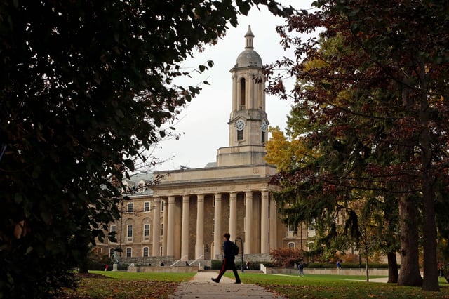 People walk by Old Main on the Penn State University main campus in State College, Pennsylvania on November 9, 2017.