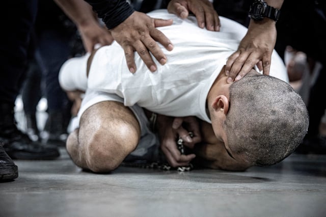 Salvadoran police officers escort an alleged member of the Venezuelan gang Tren de Aragua recently deported by the U.S. government to be imprisoned in the Terrorism Confinement Center (CECOT) prison, as part of an agreement with the Salvadoran government, in Tecoluca, El Salvador, in this handout image obtained March 16, 2025. Secretaria de Prensa de la Presidencia/Handout via REUTERS