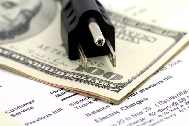 Stock image/file photo: U.S. Dollars and plug laid over a utility bill.