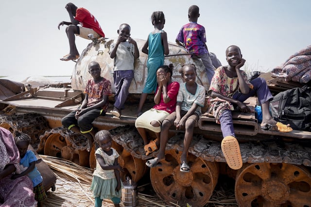 FILE - Children sit and play on the remains of a tank, at the river port in Renk, South Sudan on May 17, 2023. (AP Photo/Sam Mednick, file)