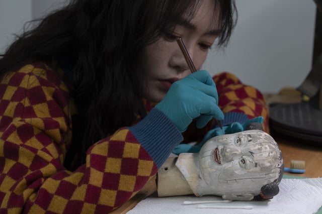 A restorer works on the head of a mechanical doll that manually moves a fan that once kept the imperial family cool on the sprawling compound of the Forbidden City also known as the Palace Museum in Beijing, Friday, Feb. 21, 2025. (AP Photo/Ng Han Guan)