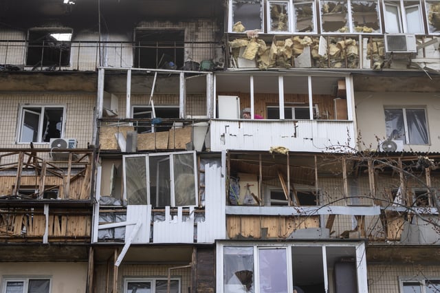 A resident cleans up the damaged apartment in a multi-storey house after Russia's night drone attack, in Kyiv, Ukraine, Sunday, March 23, 2025. (AP Photo/Efrem Lukatsky)