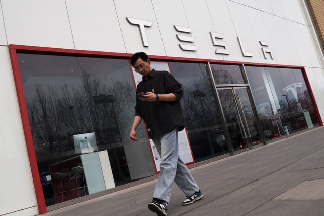 A man walks by at a store of the electric vehicle (EV) maker Tesla, in Beijing, China March 24, 2025. REUTERS/Florence Lo