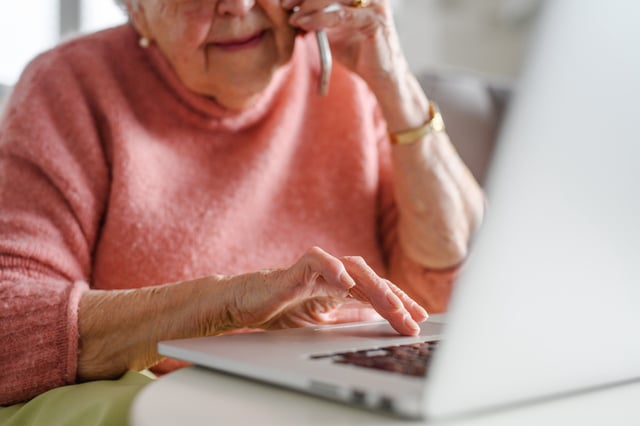 Stock image/file photo: An elderly woman using a computer while talking on the phone.