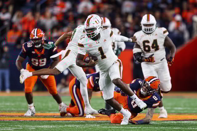 Cam Ward #1 of the Miami Hurricanes runs the ball as Justin Barron #8 of the Syracuse Orange attempts to tackle him during the third quarter at JMA Wireless Dome on November 30, 2024 in Syracuse, New York.