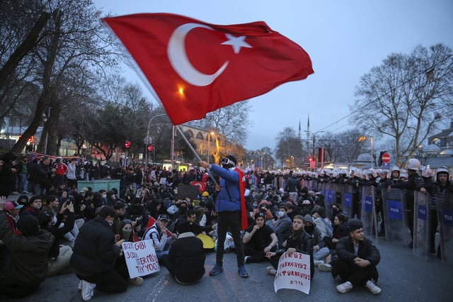 University students sit next to anti riot police officers during a protest after Istanbul's Mayor Ekrem Imamoglu was arrested and sent to prison, in Istanbul, Turkey, Monday, March 24, 2025. (AP Photo/Huseyin Aldemir)