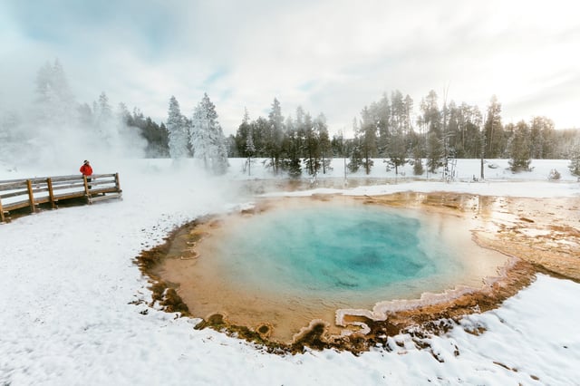 A woman visiting a hot spring in winter in Yellowstone National Park, Wyo.
