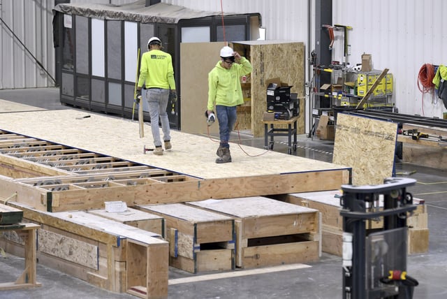 Workers construct the flooring of a modular home at the Fading West factory in Buena Vista, Colo., on Feb. 19, 2025. (AP Photo/Thomas Peipert)