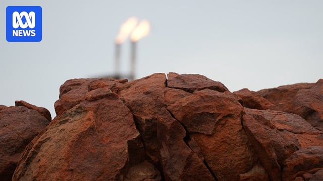Close up of a collection of jagged red rocks. In the background, two towers spitting flames.