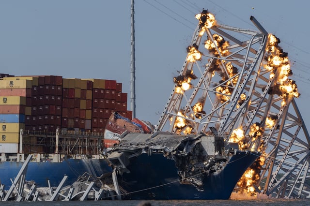 FILE - Explosive charges are detonated to bring down sections of the collapsed Francis Scott Key Bridge resting on the container ship Dali on May 13, 2024, in Baltimore. (AP Photo/Mark Schiefelbein, File)