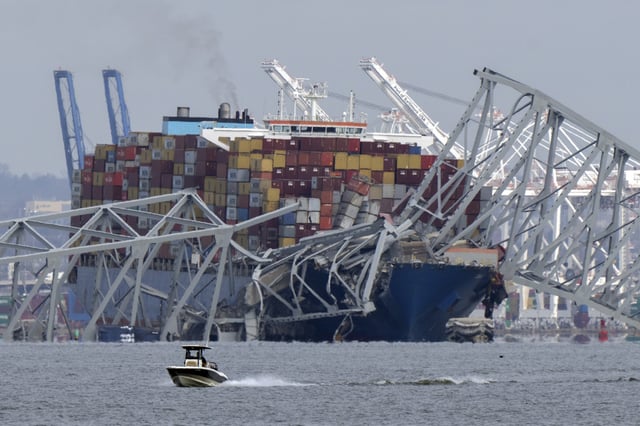FILE - A boat moves past a container ship as it rests against wreckage of the Francis Scott Key Bridge on March 26, 2024, as seen from Pasadena, Md. (AP Photo/Mark Schiefelbein, File)