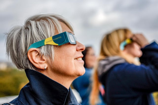 Blick auf eine partielle Sonnenfinsternis mit Schutzbrille