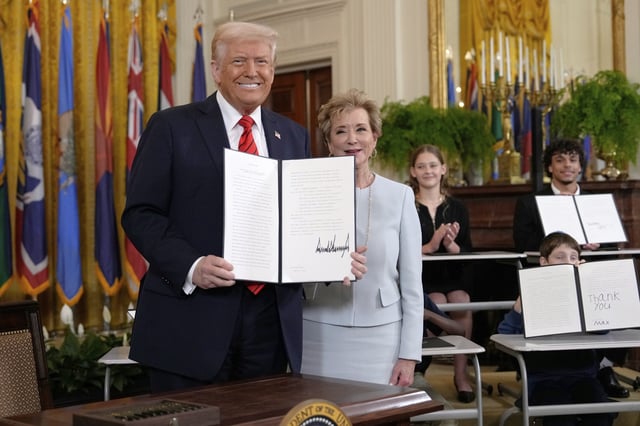 President Donald Trump holds up a signed executive order alongside Secretary of Education Linda McMahon in the East Room of the White House in Washington, Thursday, March 20, 2025. (AP Photo/Ben Curtis)
