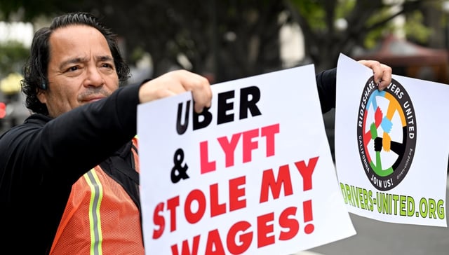 Rideshare driver Ricardo Valladares holds his signs during the rally.  Nearly 100 ridesharing drivers with Uber and Lyft from across California gathered in front of L.A. City Hall to demonstrate on Wednesday, March 26, 2025. The demonstration is taking place as State Attorney General Rob Bonta; City Attorneys Hydee Feldstein Soto (LA), David Chiu (San Francisco) and Heather Ferbert (San Diego); and attorneys for drivers, continue settlement talks with Uber and Lyft in a massive wage theft scandal that robbed drivers of billions of dollars collectively.  (Photo by Dean Musgrove, Los Angeles Daily News/SCNG)