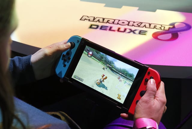PARIS, FRANCE - JANUARY 13: A visitor plays the "Mario Kart 8 Deluxe" video game on a Nintendo Switch games console during the new console's unveiling by Nintendo Co on January 13, 2017 in Paris, France. This next-generation game console, billed as a combination of a home device experience and a portable entertainment system, will be available for $ 299.99 in the US from March. (Photo by Chesnot/Getty Images)