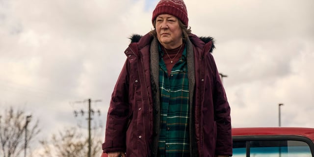 margo martindale wears a burgundy jacket and hat while standing in the cold