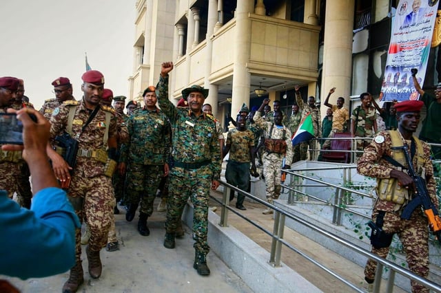 Der sudanesische Staatschef Abdel Fattah al-Burhan (M) hebt die Faust, als er umringt von Soldaten im erst kürzlich zurückeroberten Präsidentenpalast ankommt.