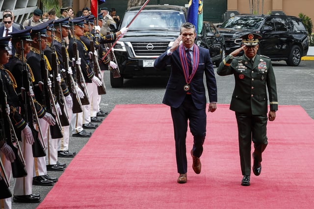 U.S. Defense Secretary Pete Hegseth, center, along with Armed Forces of the Philippines Chief of Staff General Romeo Brawner, salutes troops upon arriving at the Armed Forces of the Philippines Headquarters in Camp Aguinaldo in Quezon City, Philippines, Friday, March 28, 2025. (AP Photo/Gerard Carreon)
