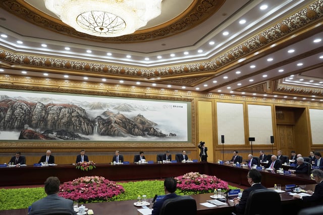Chinese President Xi Jinping, third left, and Foreign Minister Wang Yi, fourth left, meet an international business representatives during an event at the Great Hall of the People in Beijing on Friday, March 28, 2025. (AP Photo/Ng Han Guan)