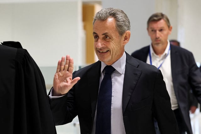 Mann mit Anzug und Krawatte, der mit seiner erhobenen rechten Hand eine abwehrende Geste macht