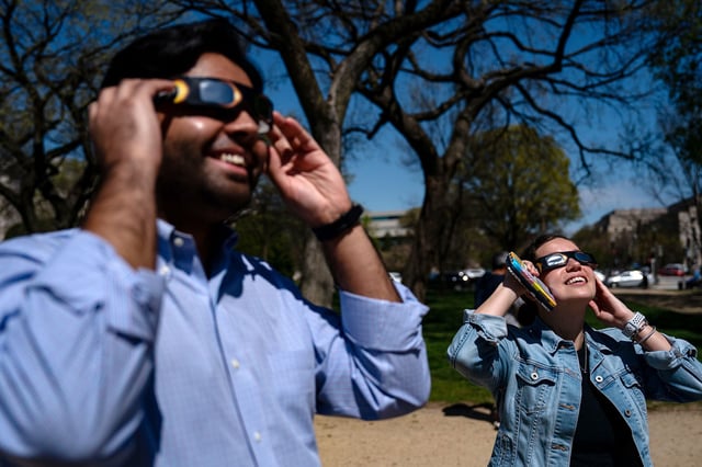 People gathered on the National Mall to view the partial solar eclipse using eclipse glasses on April 8, 2024, in Washington, DC.