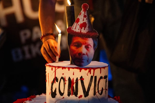 A protester lights a candle on a mock cake at a protest during the 80th birthday of former Philippine President Rodrigo Duterte, who remains in ICC custody for war crimes allegations, in Manila, Philippines, March 28, 2025. REUTERS/Lisa Marie David
