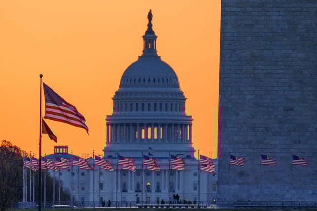 Sunrise behind the U.S. Capitol building as it illuminates the U.S. Flags circling the base of the Washington Monument on March 23, 2025, in Washington, DC.