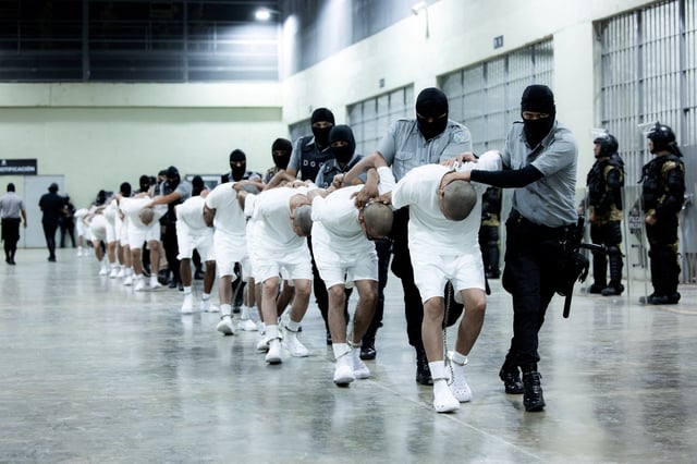 Salvadoran police officers escort alleged members of the Venezuelan gang Tren de Aragua deported by the U.S. government to be imprisoned in the Terrorism Confinement Center (CECOT) prison, as part of an agreement with the Salvadoran government, in Tecoluca, El Salvador, in this handout image obtained March 16, 2025. Secretaria de Prensa de la Presidencia/Handout via REUTERS/File Photo
