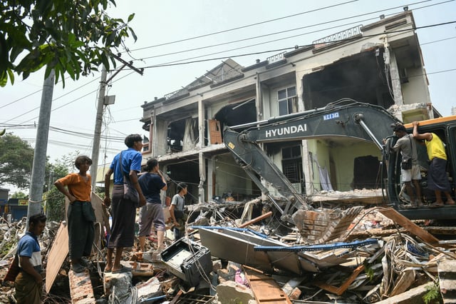 Des engins de chantier sont utilisés pour fouiller les décombres alors que des personnes cherchent des survivants à Mandalay, en Birmanie, le 29 mars 2025, au lendemain d’un tremblement de terre.
