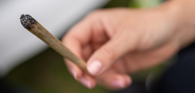 Eine Frau hält auf der Hanfmesse einen Joint in der Hand