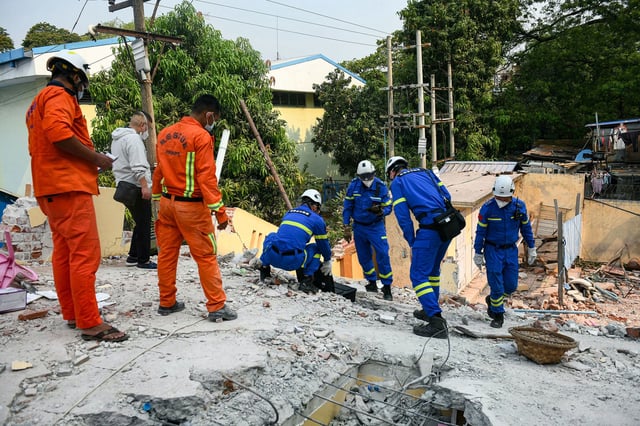 Chinese rescue team members, seen in blue, search for victims trapped in the rubble of a damaged temple in Mandalay on Saturday.