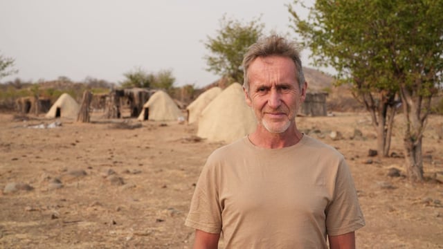 Bruce in front of the Mucubal village of Cavalecamue in Angola&#39;s Naimb Desert (Photo: Ben Cheetham/ BBC/Frank Films)