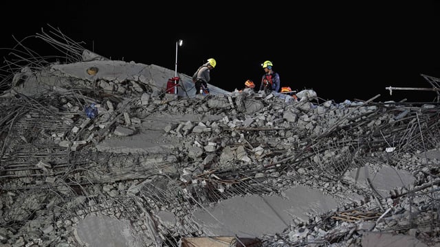 Rescue workers clear rubble on the top at the site of an under-construction building collapse in Bangkok on March 30, 2025.