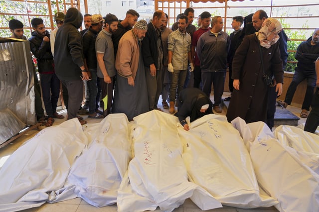 Mourners walk by the bodies of the Abu Sultan family, killed when an Israeli army strike hit their tent before their burial at the hospital in Khan Younis, southern Gaza Strip, Sunday, March 30, 2025. (AP Photo/Abdel Kareem Hana)