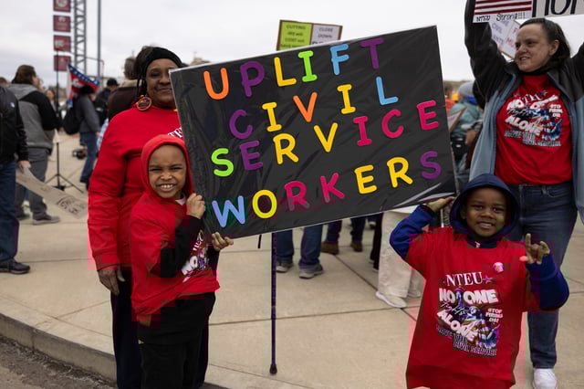 Denise Davis, a retired federal employee and NTEU union member, looks on as her great grandsons' Deondre and Montrell Griffin hold a sign during a rally across the street from the Internal Revenue Service (IRS) headquarters, in support of the civil service in the wake of mass firings, and organized by the National Treasury Employees Union (NTEU) in Kansas City, Missouri, U.S. March 15, 2025.  REUTERS/Chase Castor