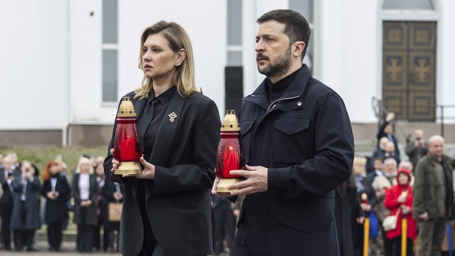 Ukraine's President Volodymyr Zelenskyy, right, and his wife Olena Zelenska carry candles to honour the memory of the victims of the Russian occupation at a memorial in the town of Bucha.