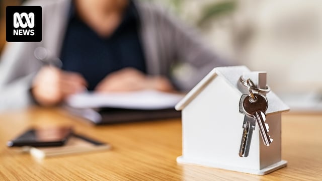 A home buyer looks at documents. In the foreground of the image is a model house and keys.