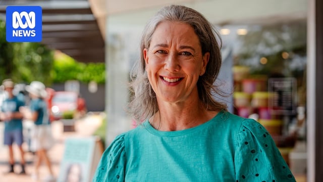 A woman wearing a teal shirt smiles.